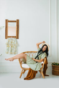 Beautiful pregnant woman smiles while lying on a wicker chair at home