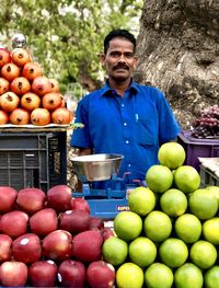 Portrait of man standing by fruits for sale at market stall