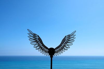 Close-up of bird on beach against clear blue sky