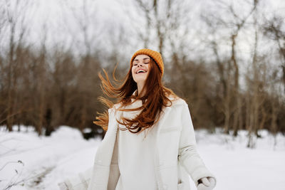 Portrait of young woman standing on snow covered field