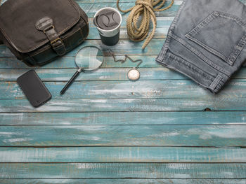 High angle view of jeans with mobile phone and rope on wooden table
