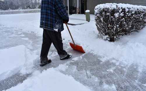 Low section of man cleaning on snow covered yard