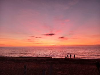 Silhouette people at beach against sky during sunset