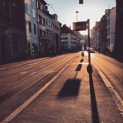 Empty road amidst buildings on sunny day