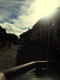 People walking on street by buildings in city against sky