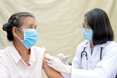 Doctor wearing mask vaccinating patient