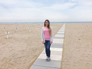 Full length of portrait of woman standing at beach