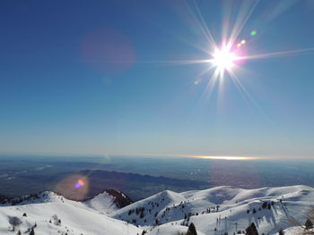 Scenic view of snow covered mountains against bright sun