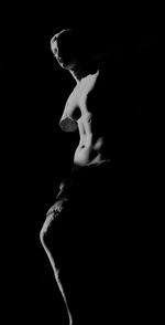 Close-up of young woman standing against black background