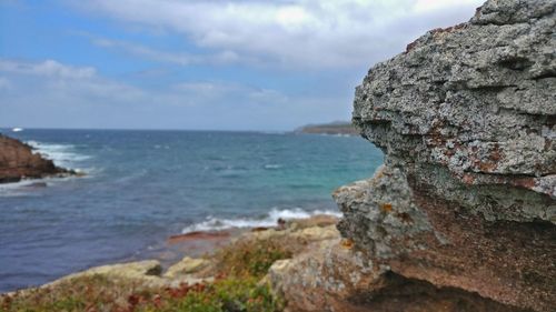 Close-up of rock by sea against sky