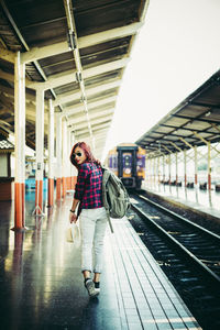 Full length of young woman walking at railroad station platform