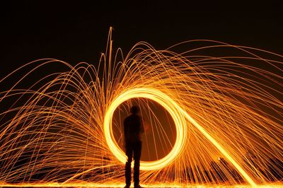 Silhouette person spinning wire wool at night