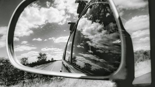 Reflection of trees on side-view mirror of car