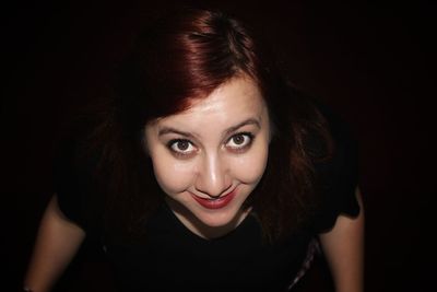 High angle portrait of smiling young woman over black background