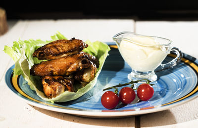 High angle view of chicken wings with cream and cherry tomatoes in plate on table