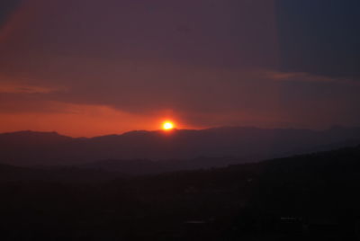 Scenic view of silhouette mountains against orange sky