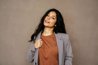 Portrait of smiling young woman against gray background