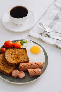 Breakfast plate with cup of black coffee, grilled sausage and whole wheat toast