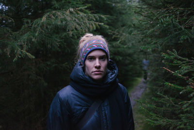 Portrait of mature woman standing by tree in forest