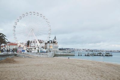 Ferris wheel on beach against sky