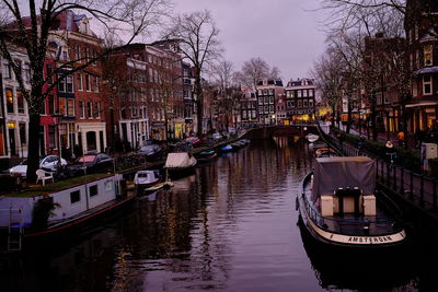 Sailboats moored in canal amidst buildings in city