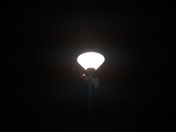 Low angle view of silhouette lights against sky at night