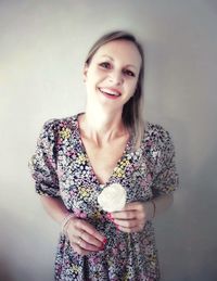 Portrait of smiling young woman standing against wall