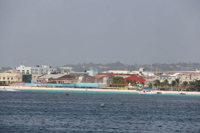 Scenic view of sea against buildings in city against clear sky