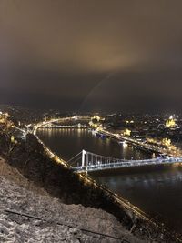 Illuminated bridge over river in city against sky at night