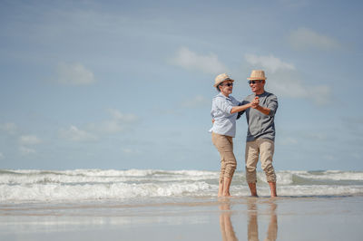 Full length of men standing at beach against sky