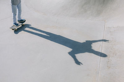 Shadow of man with skateboard on sunny day