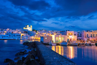 Buildings by river against sky