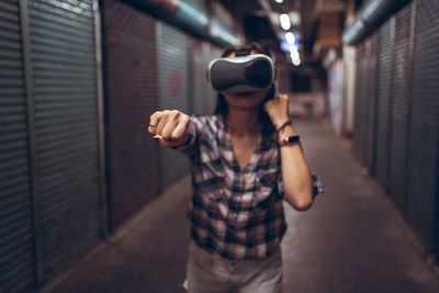 Calm female standing on narrow shabby street and experiencing virtual reality while wearing wireless vr goggles