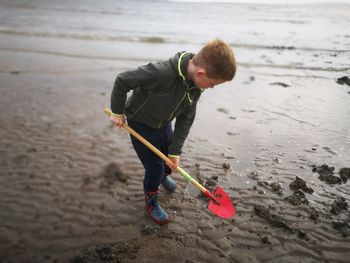 Boy playing with shovel at beach