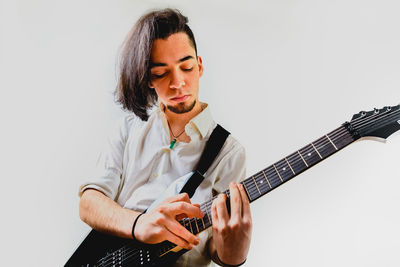 Young man playing guitar against white background