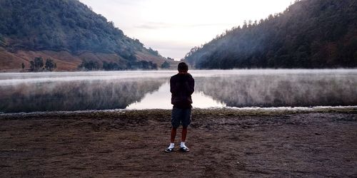 Full length of man standing by lake against mountains