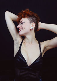 Portrait of young woman standing against black background