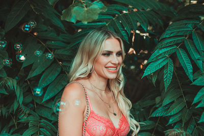 Close-up of bubbles by smiling woman standing against plants