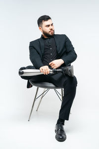 Young man sitting on chair against white background