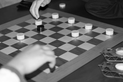 Cropped hands of people playing chess at home