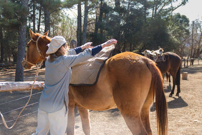 Rear view of woman with horse standing on farm