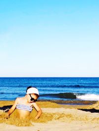 Man wearing hat on beach against clear sky