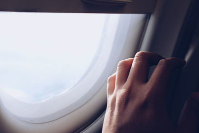 Cropped image of person touching airplane window