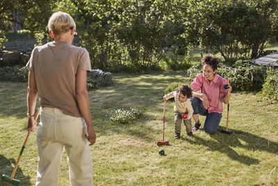 Mother with toddler playing croquet in garden