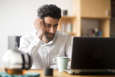 Portrait of businessman at desk looking at laptop