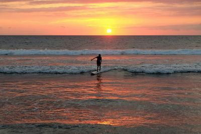 Silhouette of man standing on beach during sunset