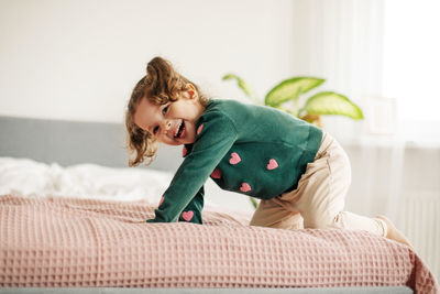 A charming little girl jumps on the bed and laughs