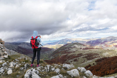 Rear view of man standing on mountain against sky