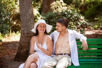 Young couple in love together on a park bench in light clothes on a summer day
