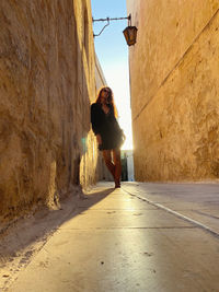 Full length of woman standing amidst alley